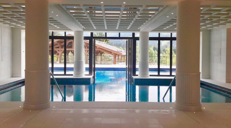 A swimming pool area with columns and ceiling